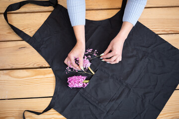 pink flowers on a black apron on a wooden background