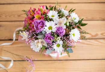 bouquet of wildflowers in a box on a wooden background