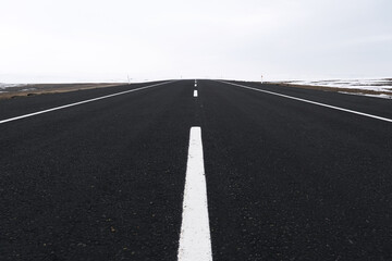 Fototapeta premium Close up View of an emtpy asphalt road with lanes and snow in winter