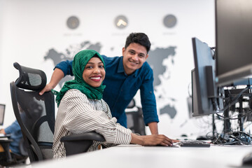 Fototapeta na wymiar Multiethnic startup business team Arabian woman wearing a hijab on meeting in modern open plan office interior brainstorming, working on laptop and desktop computer. Selective focus 