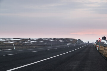 Diagonal view of an emtpy asphalt road with lanes and snow in winter