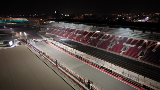 Aerial view of Dubai Autodrome on straight, grand stand, racing during night endurance competition