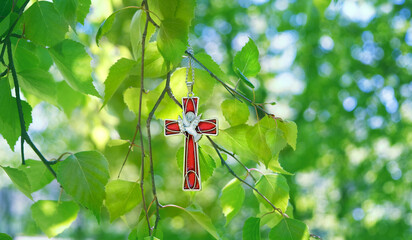 Christian cross with image of a dove on birch branches, abstract blurred green natural background. symbol of Holy Spirit. Holy Trinity Sunday, festive Pentecost day. Faith in God, Church holiday conce