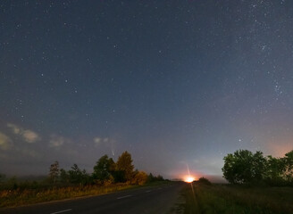 Comet Neowise C2020 F3 as it flies overhead in the summer sky over over meadow near countryside road, Lviv Region, Ukraine.