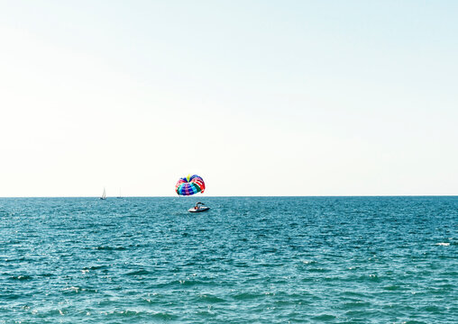 parasailing multicolored rainbow parachute behind boat over blue turquoise sea landscape summer activities copy space selective focus