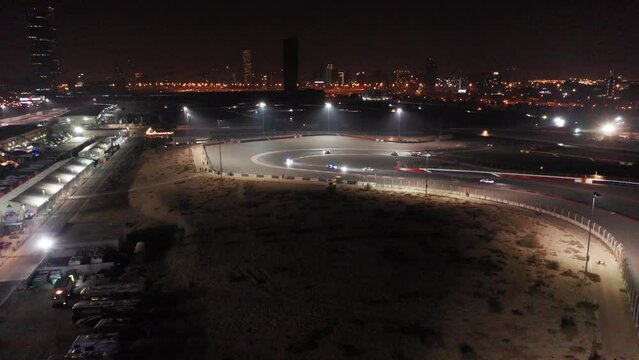 Aerial view of car racing at hairpin, Dubai Autodrome race track during night endurance competition