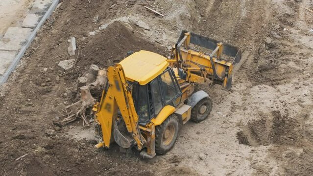 Excavator moves the ground with a heavy bucket towards the pile