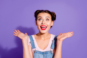 Photo of astonished funky girl raise hands look interested up empty space isolated on violet color background