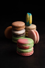Blurred image of multi-colored macaroоns on a black background. Sweet food.