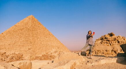 Tourist woman make photo on phone background pyramid of Egyptian Giza, sunset Cairo, Egypt