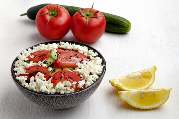 Bowl with chopped tomatoes and cucumbers, cottage cheese and black cumin seeds