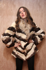 Portrait of a beautiful fashion girl brown-haired in the studio in a fur coat