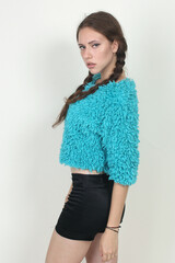 Portrait of a beautiful fashion girl brown-haired in the studio in a shorts and a blue sweater