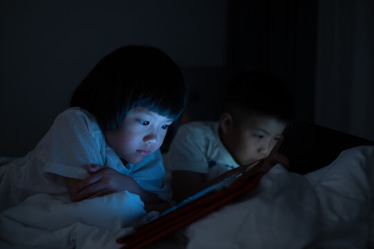 Kid Watching Tablet On The Bed At Night Time
