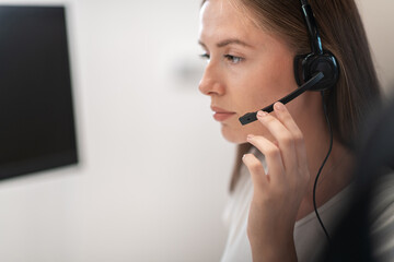 Helpline female operator with headphones in call centre.Business woman with headsets working in a call center. Selective focus 