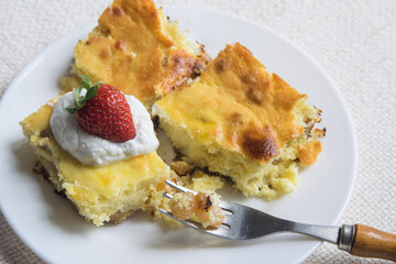 Homemade cottage cheese casserole served with strawberry and sour cream, selective focus