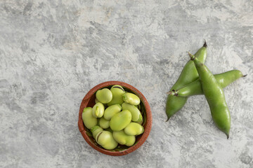 composition of peeled and shelled broad beans on a gray texture and copy space