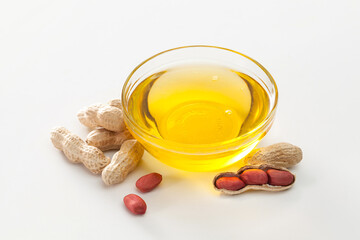 peanut oil in a glass bowl and peanuts on white background.