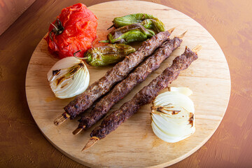 Adana kebap view with tomato, onion and green pepper.