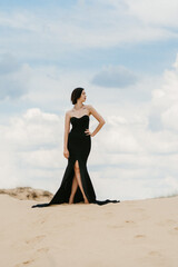 Fototapeta na wymiar girl in a black long dress in a sandy desert