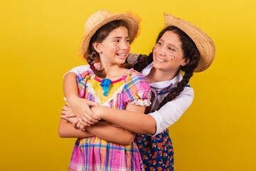 sisters and friends, wearing typical clothes of the Festa Junina. Hugging, smiling. united,...