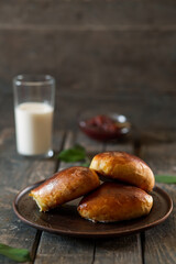 Baked pies with cherry jam in a cut on a brown clay plate on a wooden table
