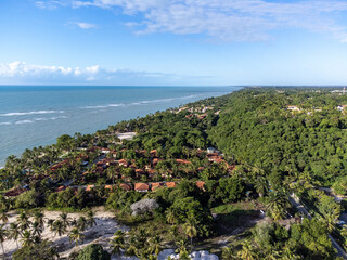 Fototapeta na wymiar Wonderful paradise beach with the summer sun rising in the middle of the Atlantic Forest. Tourist town Arraial D'Ajuda, Brazil, South America. Aerial drone view.