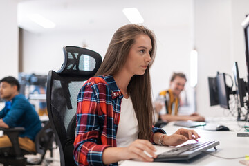 Casual business woman working on desktop computer in modern open plan startup office interior....