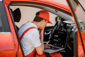 Car mechanic is using an laptop computer to check the car errors and problem and fix it. . - obrazy, fototapety, plakaty