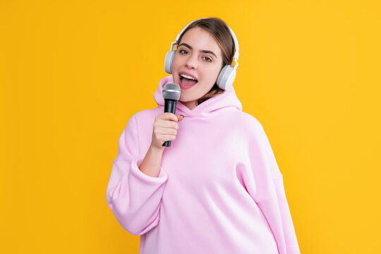 singer girl in headphones with microphone on yellow background