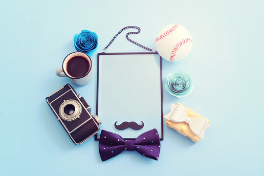Father's day concept. bow tie, funny moustache and empty frame with copy space over blue background. top view, flat lay