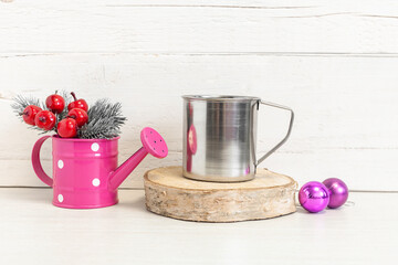 Metal mug on the table with balls and fir branches.