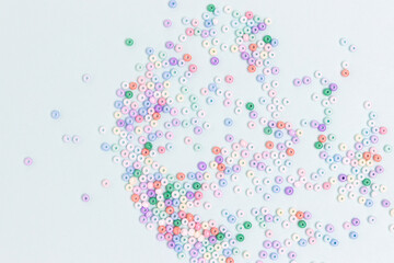 Multicolored beads scattered on a blue pastel background. Equipment for handmade accessories.