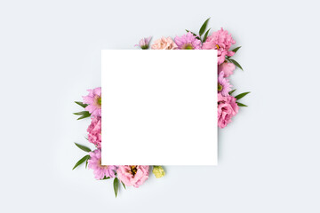 Square paper card with border frame made of eustoma flower on a blue pastel background. Festive concept with copyspace.