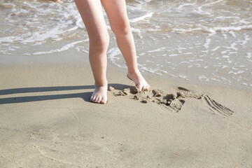 Feet of a child on the sand beach	