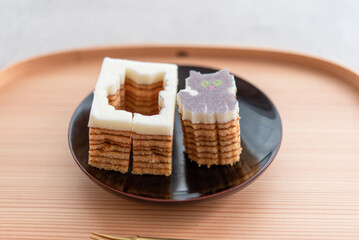 木のお盆と黒い皿に乗った猫の型抜きバウムクーヘン	