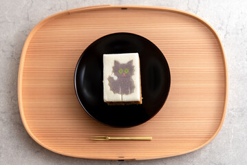 木のお盆と黒い皿に乗った猫の型抜きバウムクーヘン
