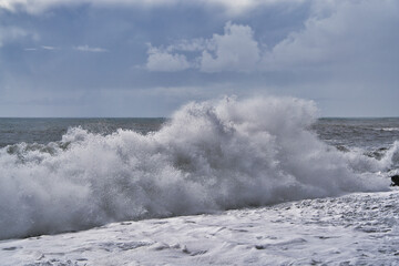 Waves breaking on a beach in sea with silver clouds on madeira, Portugal