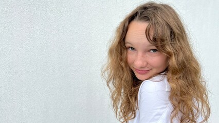 a girl on a white background in a white blouse, fair-haired, shows different cheerful emotions, she...