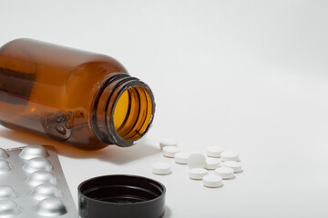 open brown pill bottle with white pills isolated on a white background