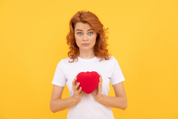 shocked woman presenting red heart on yellow background, sweetheart