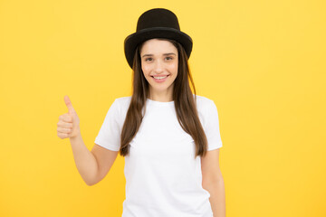 Woman in magician top hat, black vintage cylinder cap on yellow background. Girl circus performer with headwear for magic tricks. Teen girl in illusionist hat.