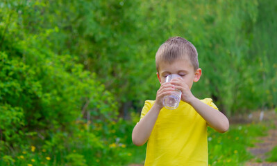 The boy drinks water from a glass. Pure water. Summer.