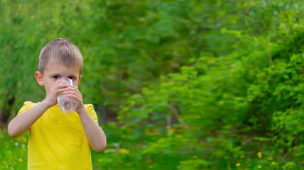 The boy drinks water from a glass. Pure water. Summer.