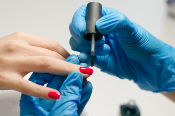 The master makes a manicure to a client in a nail salon 