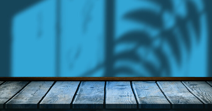 Image of leaves and window shadow over blue and wooden background
