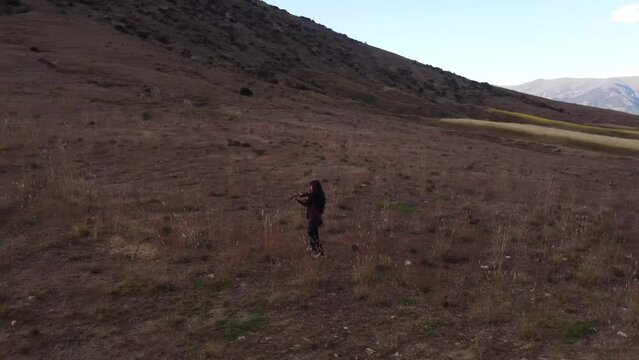 Mujer joven tocando violin en una monta&ntilde;a al atardecer. Concepto de musica y tradiciones.