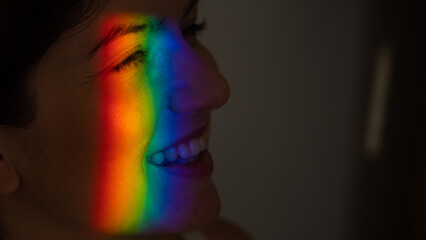 Close-up portrait of caucasian woman with ray of rainbow light on her face. 