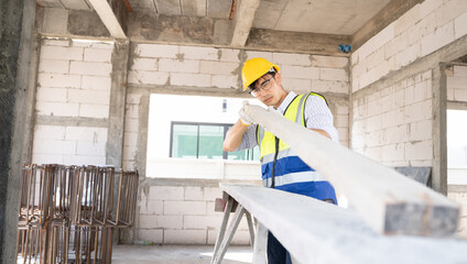 Fototapeta premium Handsome Asian Carpenter man holding a board and checking if the size is correct.