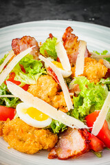 salad with fried chicken and bacon on a black background